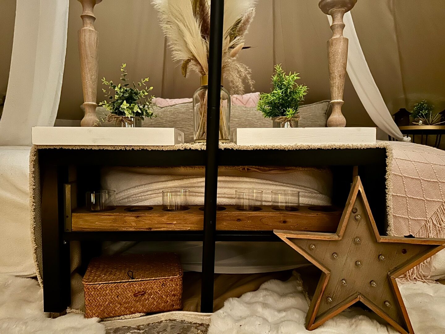 Under-bed styling detail with wood marquee star, basket, candles and pampas.